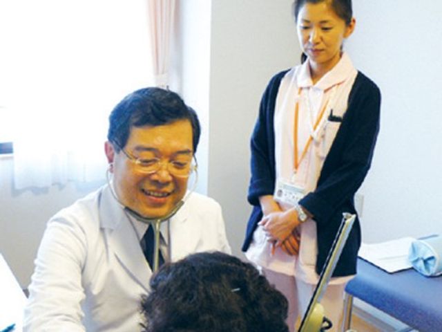 医師とスタッフの対話 医療ケア 笑顔の医師が利用者と丁寧にコミュニケーションをとる姿が印象的です。スタッフのチームワークの良さが感じられる場です。