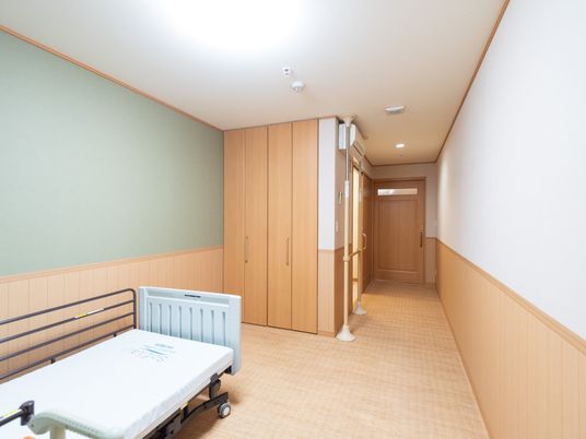 居室の木製ベッドと廊下
