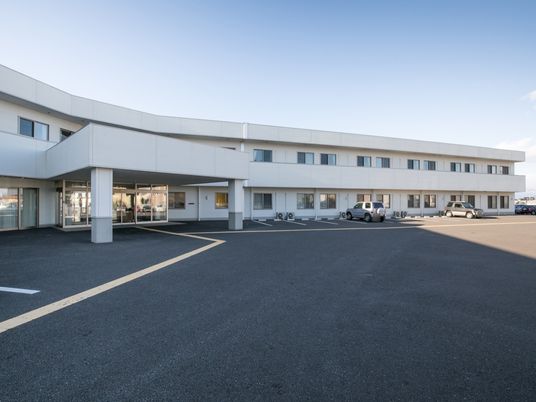 施設の写真 建物は2階建ての横に長い造りとなっており、上下への移動が少なくなっている。入口付近は駐車場となっているため、外出の際の負担も少ない。