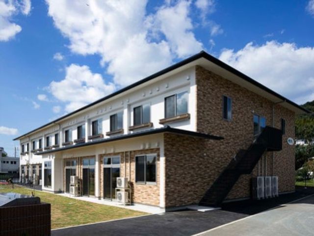 明るい外光の居室外観 外観 広々とした落ち着いた色調の建物は、清潔感があり、印象的な働き場を提供しています。余裕をもって配置されたエアコンも目に留まります。