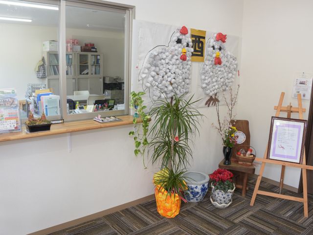 フロントの装飾と植物 受付 温かみのあるフロント周辺です。手作りの装飾があり、観葉植物が空間に彩りを添えています。