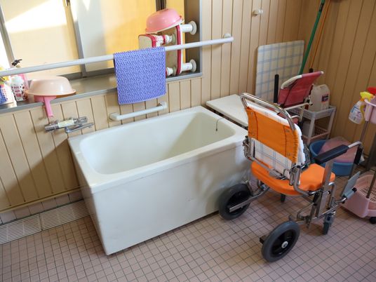 バスルームには腰掛けるためのイスがあり、壁には手すりが用意されている。また浴室専用の車椅子も置かれている。