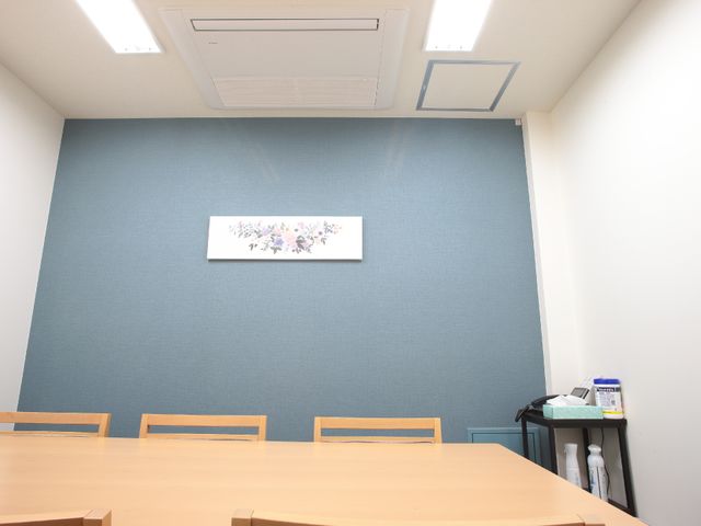 青壁とテーブルの会議室 相談室 シンプルなデザインの落ち着いた空間です。掲示物や備品を整え、活動の準備ができています。