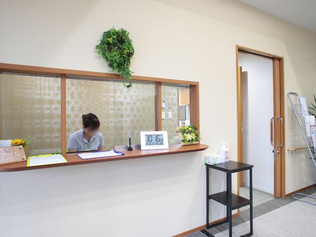 フロントで作業する人 玄関 落ち着いた雰囲気のフロントには、作業に集中するスタッフがいて、訪れた方を温かく迎えます。