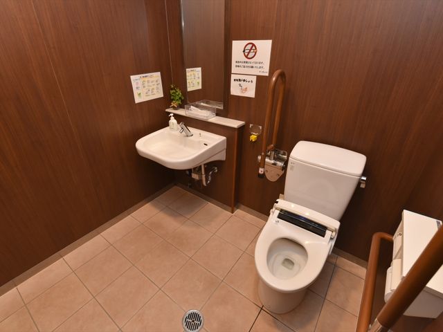 バリアフリートイレ設備 トイレ 手すり付きで安全に配慮されたキレイなトイレ空間です。利用者の快適性を重視した落ち着いた色合いが印象的です。