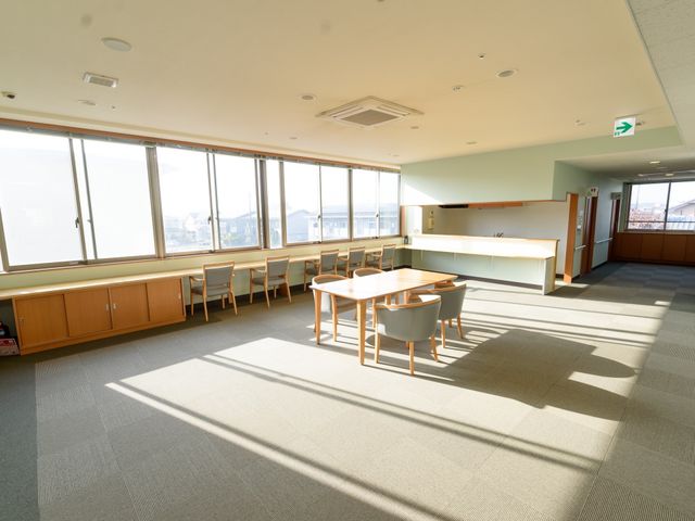 陽光あふれる食堂 リビング 広々とした窓から陽光が差し込むダイニングです。テーブルが並び、明るく開放的な雰囲気の中で食事ができます。