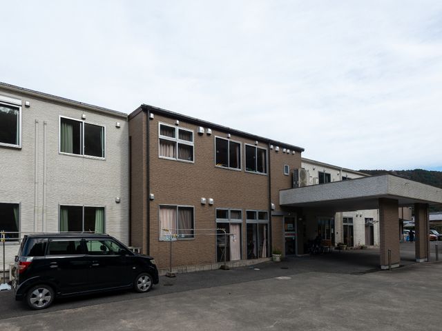 明るい外観の建物 外観 ゆったりとした駐車スペースがあり、建物へのアクセスも快適です。入口には複数の車椅子が並び、バリアフリーに配慮されています。