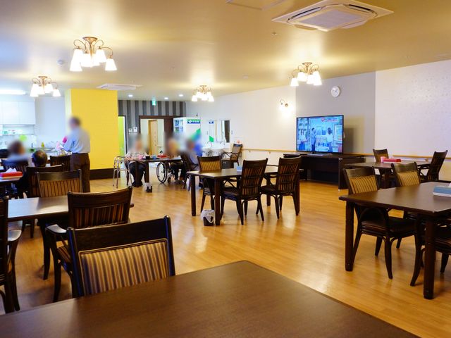 広々とした共有ダイニング ホールは集いの癒しスポット 広々としたダイニングルームで、入居者の方々がゆったりと過ごす姿が見られます。照明の温もりと木製の椅子が、落ち着いた雰囲気を醸し出しています。