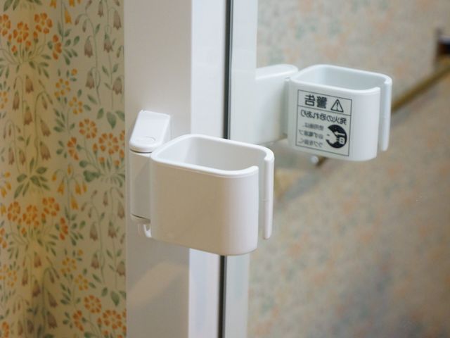 手指消毒用ディスペンサー 白いフック 清潔感のある廊下に備え付けられた消毒用ディスペンサーが、衛生的な環境維持を支えています。