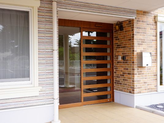 施設の写真 入り口には木目調のデザインの自動ドアがあり、来訪者が安心して中に入れるように温かみのある雰囲気を作り出しています。
