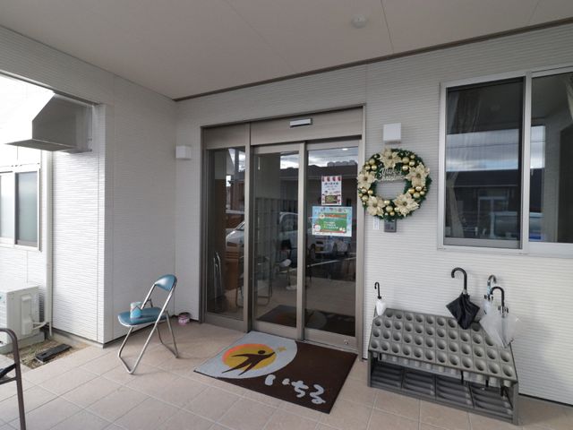 エントランスの明るい空間 玄関 お出迎えの花飾りが目を引く入口です。手すりやベンチも完備し、待ち合わせにも便利な設計となっています。