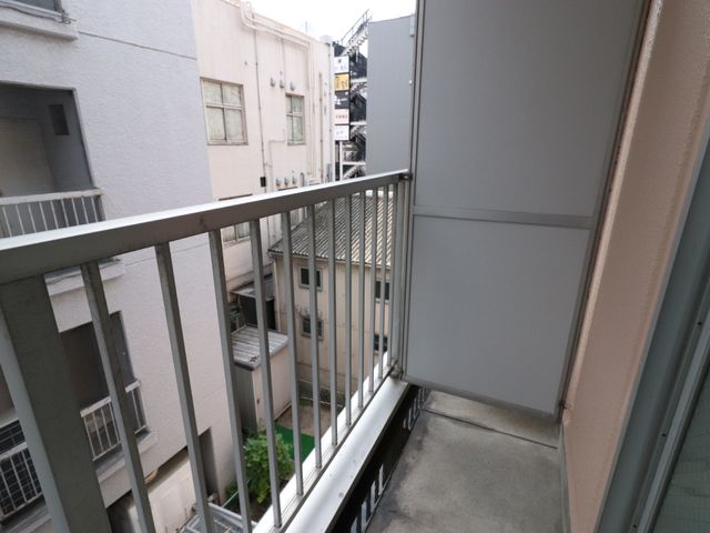 建物間の狭いバルコニー景 ベランダ 周囲の建物に囲まれた、風通しの良いバルコニーです。新鮮な空気を感じながら、ほっと一息つける空間があります。