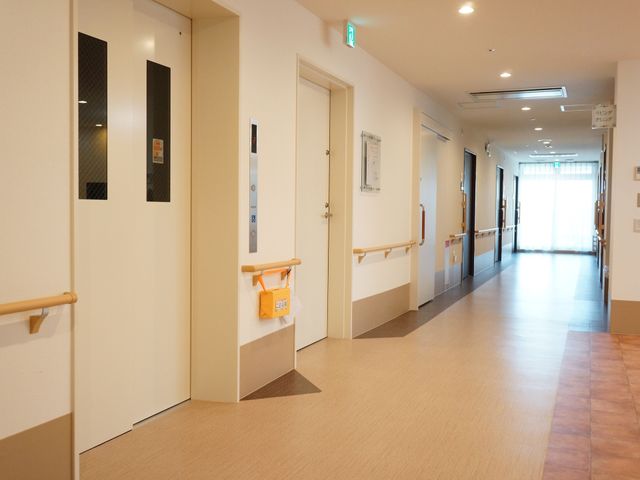 清潔感ある明るい廊下 通路 手すりが設置された温かみのある廊下は、日差しが差し込む開放感のあふれる設計です。スタッフと利用者の円滑な移動をサポートしています。