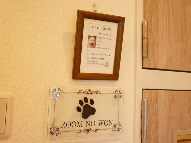 居室のドアと看板 セラピー犬 居室の入口には、心温まるペットの写真とユニークな看板が飾られ、訪れる方にやすらぎを提供しています。