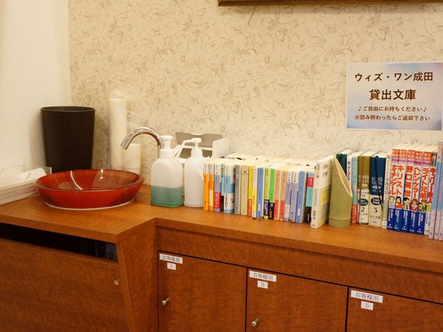 書籍と消毒設備のカウンター 玄関 清潔と読書が楽しめるスペースが整っており、ハンドサニタイザーや本が並んでいます。利用者の安全と心の豊かさを考えた環境です。