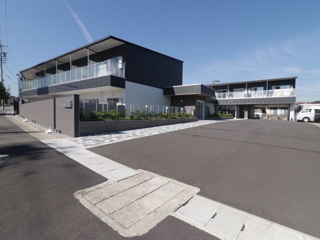 モダンな建物の外観 外観 広々とした駐車場があり、モダンな設計の建物が印象的です。明るい青空の下、清潔感のあふれる職場での勤務をご検討ください。