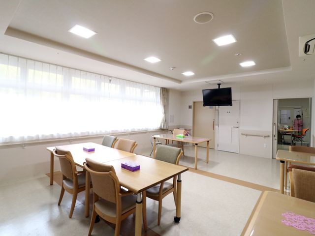 明るい共有スペースの居室 白を基調とした談話室 ゆとりあるダイニングルームで、居心地の良い食事をお楽しみいただけます。壁面には液晶テレビが設置され、共有スペースは明るく開放的です。