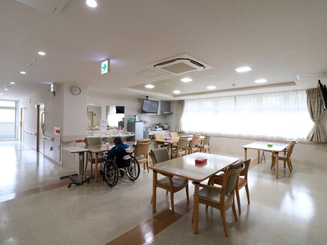 明るいダイニングエリア 広いランチルーム 利用者が車椅子でリラックスして過ごせる、広々とした食堂の様子です。天井が高く窓から自然光が差し込む開放的な空間で、居心地の良い時間を過ごせることでしょう。