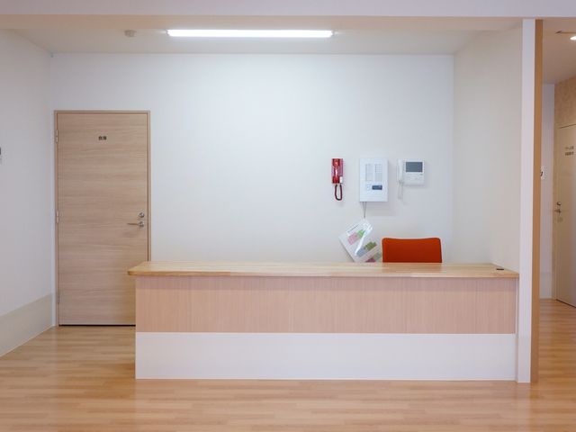 清潔なエントランスカウンター スタッフルーム 受付カウンターには必要な情報を掲示してあり、来訪者が迷うことなく応対できる設計です。木目調が温もりのある迎え入れ空間を演出しています。