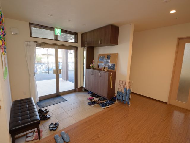エントランスの解放的な空間 玄関 広々として明るいエントランスは来訪者を温かく迎え入れます。整然と並べられた靴から訪れる人々の多さが伺えます。
