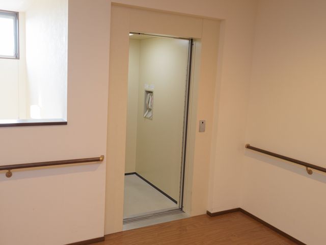 手すり付きのエレベーター入口 エレベーター 手すりが設置された広々としたエレベーター入口は、利用者の移動をサポートします。安全かつ快適にご利用いただける設計になっております。