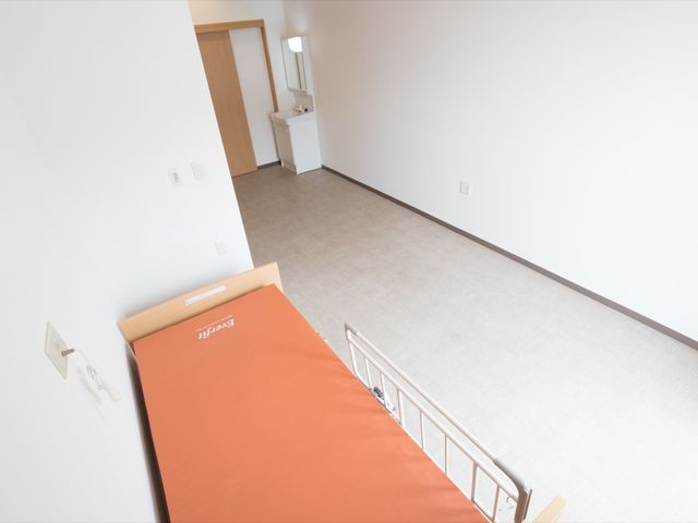 シンプルな居室 居室 広々として明るい居室は、落ち着いた色合いで、快適な生活空間を提供しています。必要最低限の家具が配置され、ゆとりを感じさせる造りです。
