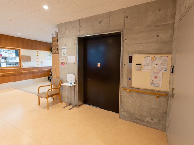 エレベーター脇の空間 エレベーター 待合椅子と掲示物が設けられたエントランスエリアです。待ち時間も快適に過ごせる配慮がされています。