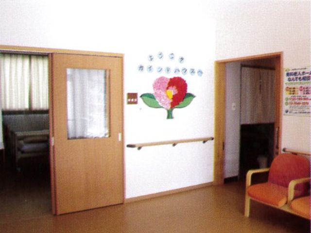 壁に花の絵が飾られた廊下 通路 温もりのあるデザインで、安らぎを感じる空間です。廊下には明るい色合いの花の絵があり、訪れる人の目を和ませます。