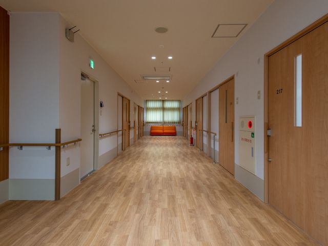廊下の明るく清潔な様子 廊下 手すり付きの広々とした廊下は落ち着いた色合いで、静かな雰囲気を保つ設計になっています。安全かつ快適にお過ごしいただける環境です。