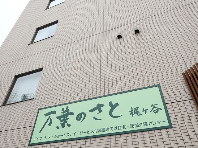 建物外観と看板 外観 土色のタイルで覆われた建物の正面に、サービス内容が記された緑色の看板が目を引きます。落ち着いた色合いが周囲の環境に調和しており、温かみのある印象を与えます。