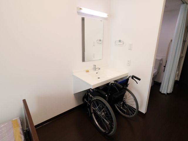 洗面台と車椅子の居室 居室用洗面所 広々とした洗面台が設置されており、まわりに余裕のスペースがあるので、車椅子をご使用の方も快適にお過ごしいただけます。