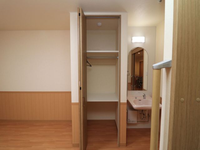 居室内の洗面台とクローゼット クローゼット 清潔感のある居室で、衣類や小物を整理できる収納スペースが確保されており、日々の生活に便利な設備を整えています。