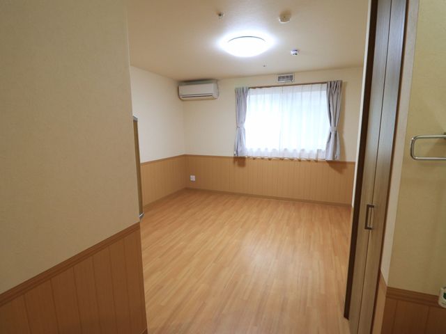 木目調の床の居室 居室 広々とした明るい居室は、自由にレイアウト可能な空間を提供しています。快適な個人の時間を過ごせる場所です。