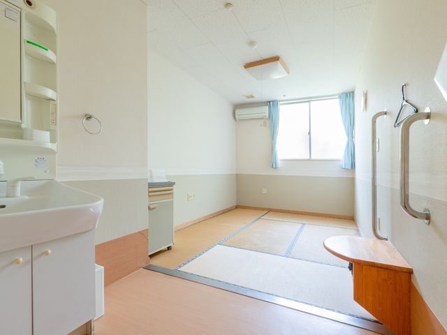 和風居室の明るい空間 居室 清潔感のある明るい居室で、窓からの光が部屋全体を優しく照らしています。手すりや畳のスペースが落ち着いた環境を提供しています。