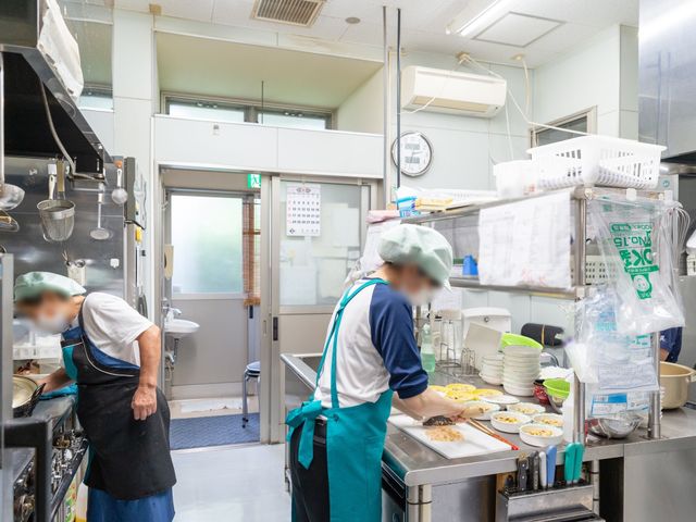 調理中のキッチン風景 調理室 スタッフが手際良く調理を行う清潔なキッチンです。栄養バランスを考えた食事の提供に力を入れています。