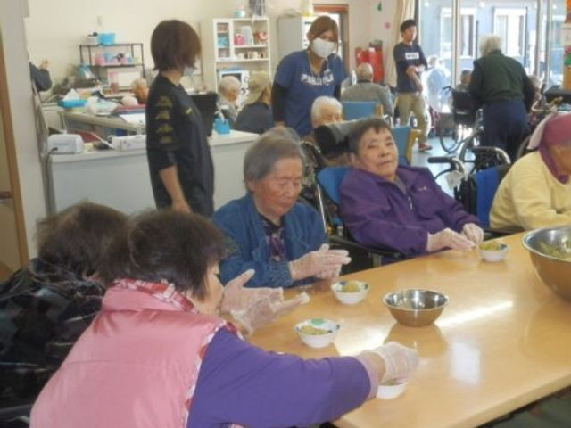 活動する利用者とスタッフ 料理 和やかな雰囲気のダイニングで利用者が手作り活動を楽しんでいます。スタッフがそばで支援をしており、利用者が積極的に参加できる環境が整っています。