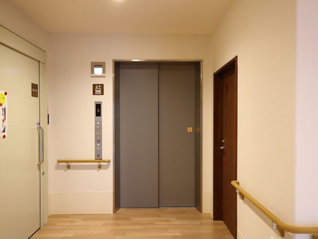 清潔感のある廊下 エレベーター ハンドレールが設けられた落ち着いた雰囲気の廊下です。段差の少ない設計で、どなたでも安心して移動できます。