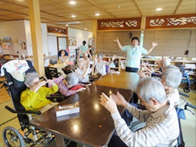 活動する人々とスタッフ 共有スペース 笑顔あふれる食堂で、スタッフが優しくサポートしながら活気ある時間を提供しています。利用者さま同士も和やかに交流されています。