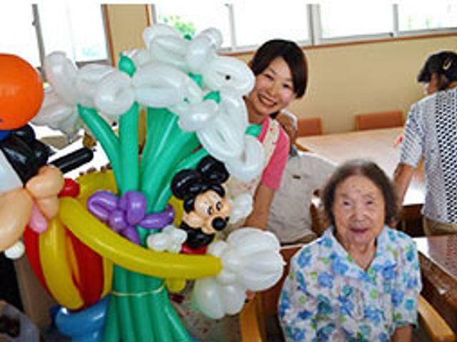 笑顔のスタッフと高齢者 行事 活気のある多目的室で楽しいアクティビティを提供しており、利用者の方々の笑顔あふれる場です。スタッフとのふれあいも充実しています。