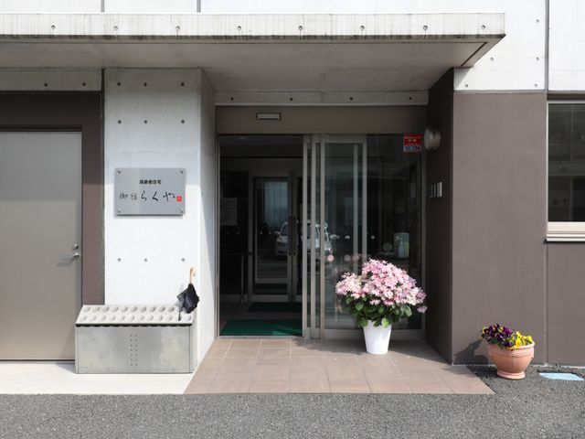 入口に花が添えられた建物 玄関 清潔感のあるエントランスには、季節の花が飾られ、訪れる人々を温かく迎えています。