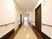 サムネイル 掃除が行き届き、壁と天井がアイボリーの明るい廊下である。居室のドアは焦げ茶色で、廊下のアクセントになっている。