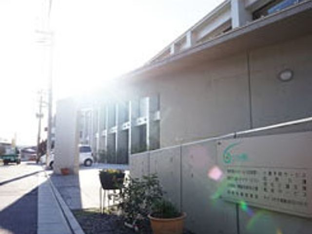 日差しが輝く施設外観 デイサービスセンター 清潔感のある外観の建物前には、温かな日差しが差し込み、訪れるすべての方をやさしく迎えます。