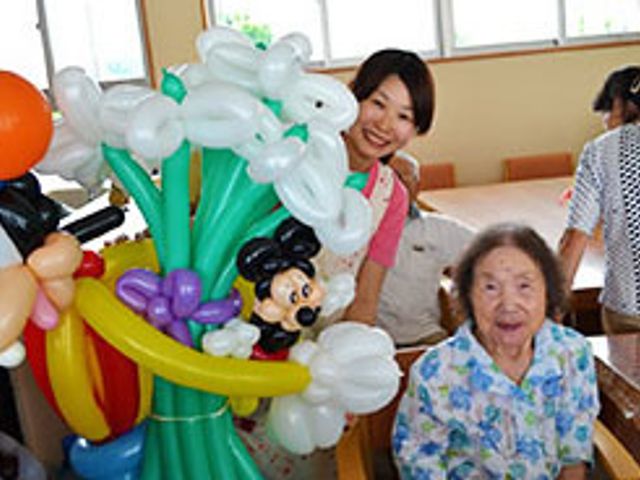 楽しい風船アート活動 イベント カラフルな風船アートを楽しむ笑顔のスタッフとご利用者さまです。創造性を高め、コミュニケーションも生まれる温かい空間がここにあります。