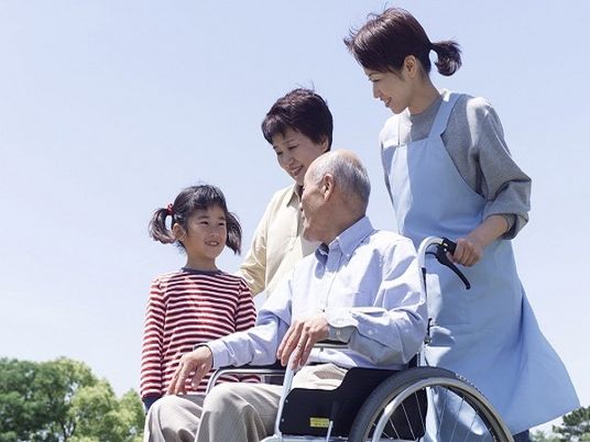 車椅子の高齢者とスタッフ、子供