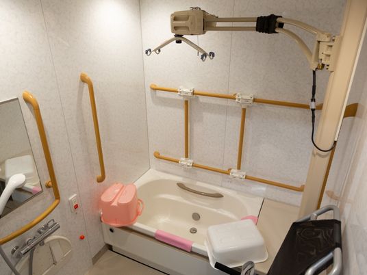 リフトが設置された機械浴室。壁にはいくつも手すりが設置されており、桶やシャワーチェアが準備されている。
