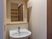 サムネイル 居室の一角に備え付けられたシンプルな鏡付きの洗面台は、蛇口がレバー式で使いやすい。向かい側には収納棚が見える。