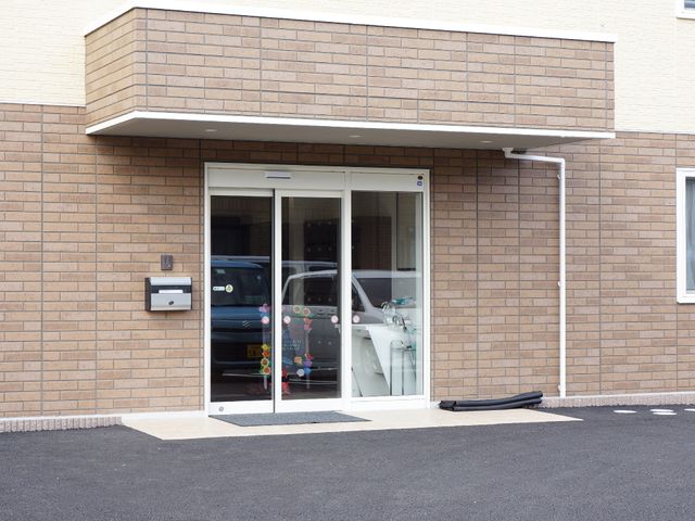 玄関に停まる車 玄関外側 明るいエントランス前には車が停まっており、来訪者を歓迎している様子です。