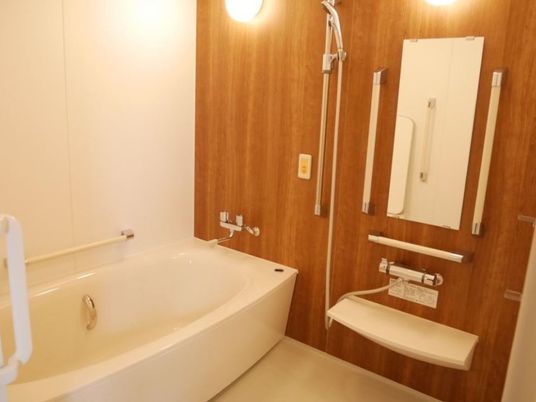 白い浴室にアクセントを加える木目調の壁が暖かな印象を与える。浴槽の中にも手すりが付いており、安心で快適な入浴を助ける。