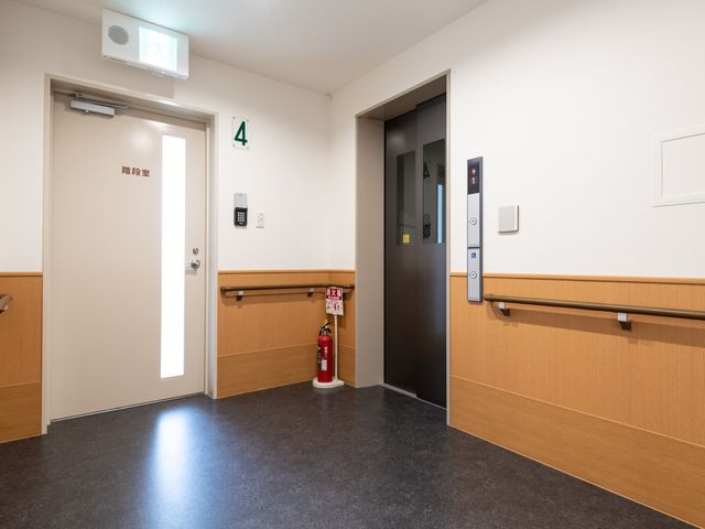 廊下とエレベーター 通路 手すり付きの清潔感ある廊下です。床の反射やエレベーターの位置が見やすく、安全に移動できる設計になっています。