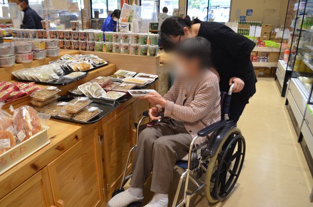 車椅子で買い物支援の様子 リビング 広々とした売り場で、スタッフが親切に買い物をサポートしています。快適な環境が整っています。
